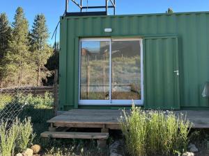 een groen tiny house met een houten terras bij Karü in Aluminé