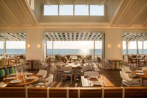 Naples Beach Club, A Four Seasons Resort في نيبلس: مطعم مع طاولات وكراسي والمحيط