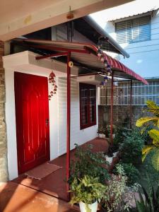 a red front door of a house with plants at Gruham Homestay in Jorhāt