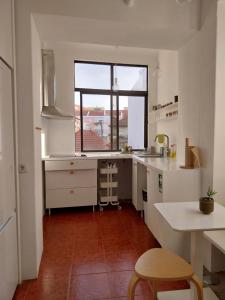 a kitchen with white counters and a large window at Stylish Cacilhas rooms near the ferry to central Lisbon in Almada
