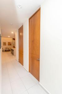 a hallway with a wooden door and a white tile floor at Casa Itzae Hotel Boutique in Mérida