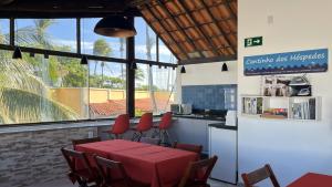 a dining room with a red table and chairs at FAROL BEACH Suítes in Salvador