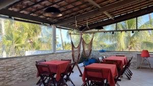 a restaurant with red tables and chairs and windows at FAROL BEACH Suítes in Salvador