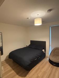 a bedroom with a black bed and a chair at Modern-Spacious Dublin Apartment in Dublin