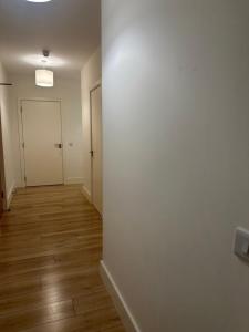 an empty hallway with a white wall and wooden floors at Modern-Spacious Dublin Apartment in Dublin