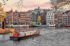 un barco en un río en una ciudad con edificios en Leonardo Eden Hotel Amsterdam City Center, en Ámsterdam