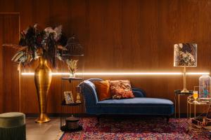 una habitación con una silla azul y un jarrón de flores en Leonardo Eden Hotel Amsterdam City Center, en Ámsterdam