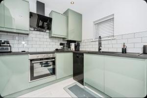 Stunning, Newly Refurbished 1-Bedroom Flat in Gravesend في غريفسيند: مطبخ أبيض اللون بخزائن خضراء وموقد