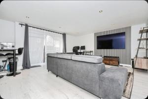 Stunning, Newly Refurbished 1-Bedroom Flat in Gravesend في غريفسيند: غرفة معيشة مع أريكة كبيرة وتلفزيون بشاشة مسطحة