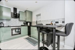 Stunning, Newly Refurbished 1-Bedroom Flat in Gravesend في غريفسيند: مطبخ مع دواليب خضراء وطاولة مع كراسي +6 صور
