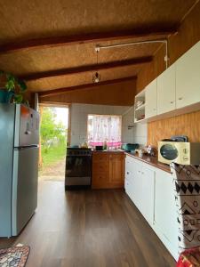 a kitchen with white cabinets and a stainless steel refrigerator at Cabaña entre mares Huelmo in Puerto Montt
