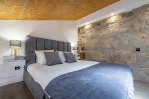 ein Schlafzimmer mit einem großen Bett mit einer Steinwand in der Unterkunft Lapa 4 House in Porto