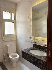 a bathroom with a toilet and a sink and a window at Stella Heights in El Alamein