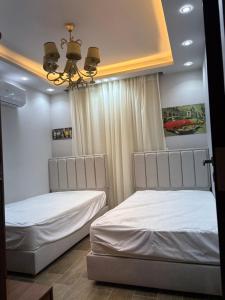 a bedroom with two beds and a chandelier at Stella Heights in El Alamein