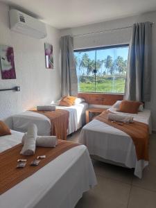 a hotel room with three beds and a window at Pousada Brisa e Mar in Praia do Frances