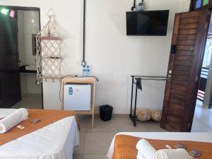 a room with two beds and a tv on the wall at Pousada Brisa e Mar in Praia do Frances