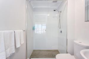 a white bathroom with a shower and a toilet at Sunset Marina Escape Freo-amazing Views & Central in Fremantle +29 photos