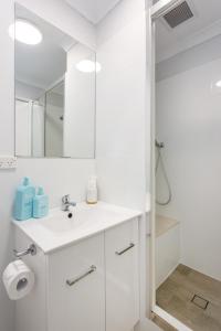 a white bathroom with a sink and a mirror at Sunset Marina Escape Freo-amazing Views & Central in Fremantle
