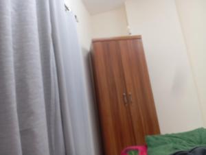 een houten kast in een kamer met een gordijn bij Happy living room stay in Sharjah