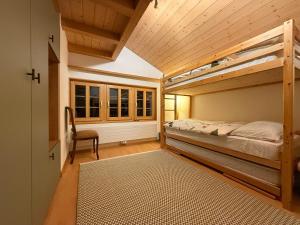 a bedroom with two bunk beds and a chair at Renovated traditional chalet in car-free Mürren in Mürren