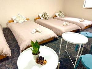 a room with three beds and a table with a plant at MY HOUSE たいみんぐ kuwana 長島15分 名古屋20分 桑名駅徒歩3分 in Kuwana