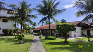 Duplex com Hidro em Condomínio Luxo com 3 Praias في انغرا دوس ريس: ساحة فيها نخيل ومبنى