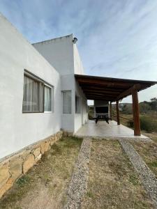 a white house with a wooden roof at Del valle cabañas in Tanti