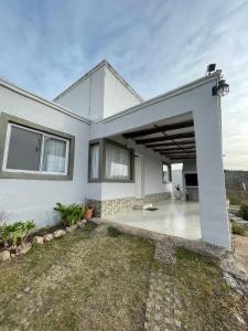 a white house with a covered patio at Del valle cabañas in Tanti