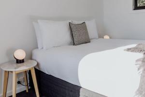 ビチェノにあるPods on Fraserの白いベッドとサイドテーブルのある寝室