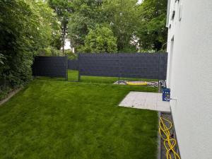 a backyard with a fence and a green lawn at Privatunterkunft Neubau mit Garten Mainz Wiesbaden Frankfurt Airport in Bischofsheim
