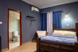 a bedroom with blue walls and a bed and a bathroom at Bluegreen Guest House in Accra +3 photos