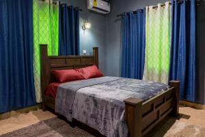 a bedroom with a bed with blue and green curtains at Bluegreen Guest House in Accra
