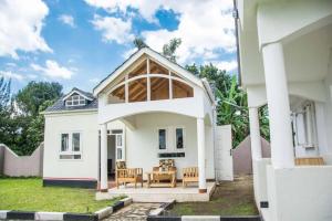 a white house with a porch with a table and chairs at Fortbella Tourist Inn in Njara