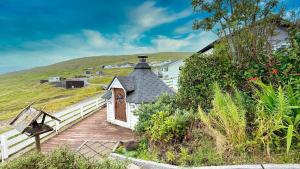 Exclusive Modern Villa with Panoramic Views في Vestmanna: مبنى أبيض صغير مع سقف على تلة