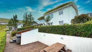 Exclusive Modern Villa with Panoramic Views في Vestmanna: بيت ابيض وفيه سياج ومقعد خشبي