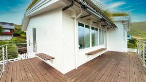 Exclusive Modern Villa with Panoramic Views في Vestmanna: منزل أبيض ذو شرفة خشبية مزودة بمقاعد +49 صورة