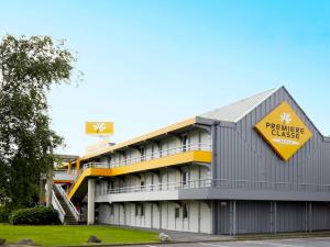 a building with a yellow sign on the side of it at Premiere Classe Beauvais in Beauvais