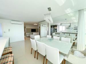 a dining room with a white table and white chairs at Alto Padrão - Balneário Camboriú in Balneário Camboriú