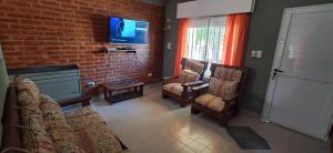 El Encuentro في لاس غروتاس: غرفة معيشة مع أريكة وكراسي وجدار من الطوب