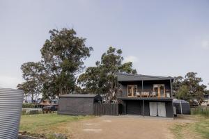 Surveyors BayにあるThe Beach Box at Big Roaring Beach Tasmaniaの庭にバルコニー付きのブラックハウス