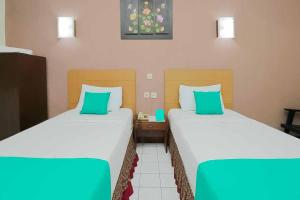 two beds in a hotel room with green pillows at Hotel Lestari Near Lippo Plaza Mall Jember in Jember