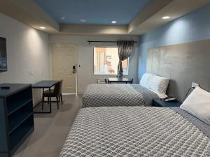 ein Hotelzimmer mit zwei Betten und einem Tisch und einem Schreibtisch in der Unterkunft Swan inn in Houston