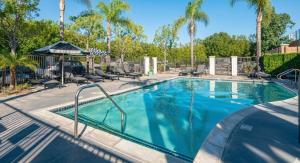 ein Swimmingpool mit Stühlen und Palmen in der Unterkunft Newly Remodeled 3BR Apt | Mins to Disney | Arcade in Yorba Linda
