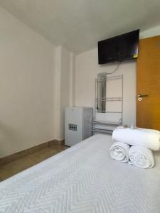 a bedroom with a white bed with a tv on the wall at Alojamiento de habitaciones Zaidín in Granada +2 photos