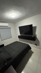Un dormitorio con una cama y un televisor de pantalla plana. en Bonita casa de lujo, en Ciudad Obregón