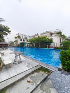 ein großer blauer Swimmingpool mit einem Tisch und Gebäuden in der Unterkunft Biệt Thự 3 Phòng Ngủ A1-03 in Ðức Hòa