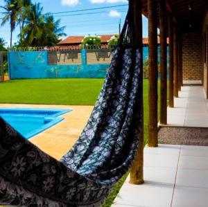 a hammock hanging from a porch next to a pool at Morada do vento in São Miguel do Gostoso