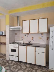 een keuken met witte kasten en een wit fornuis bij Complejo llaipen 2 confirmar reserva luego de la solicitud desde la app! in Las Grutas