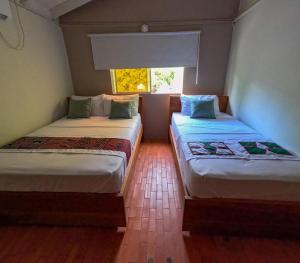 Casa Manglares Capurganá في Acanti: سريرين في غرفة بها نافذة