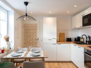 Holiday home Ahorn ground floor في Weilerswist: مطبخ مع خزائن بيضاء وطاولة وكراسي